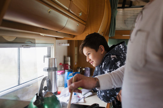 Father and soon cooking and looking out window in motor home