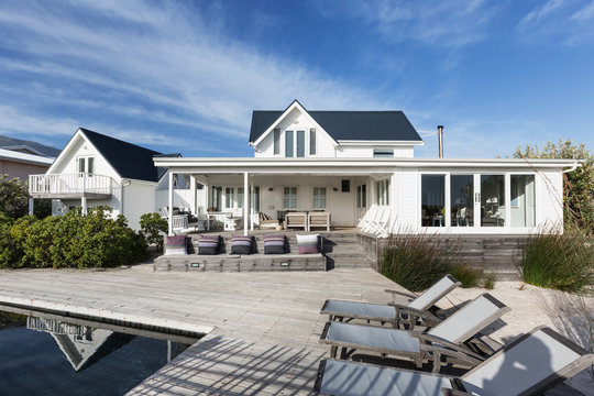 Sunny white home showcase exterior with patio and swimming pool