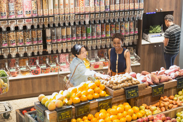 Young women grocery shopping, browsing produce in market