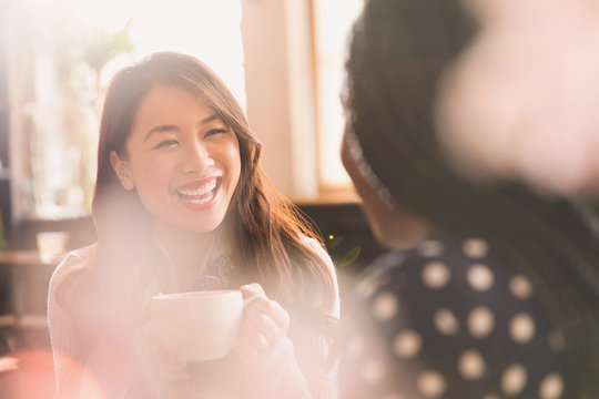 Laughing women talking and drinking coffee in cafe