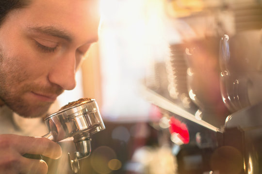 Close up barista smelling espresso grounds at espresso machine