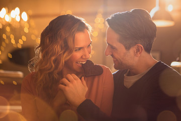 Affectionate couple biting heart-shape chocolate cookie