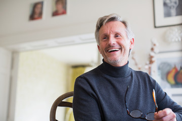 Laughing mature man holding eyeglasses