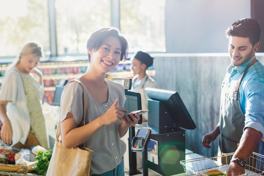 Portrait smiling young woman at grocery store checkout