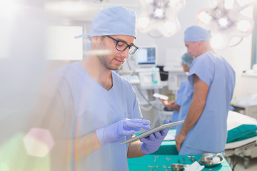 Male surgeon using digital tablet in operating room