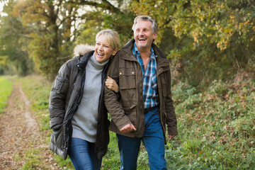 Happy, carefree mature couple walking arm in arm in autumn park