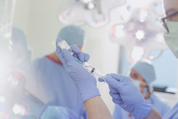 Male anesthesiologist with syringe preparing anesthesia medicine in operating room