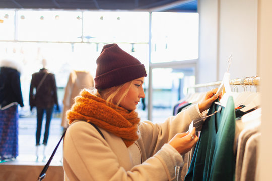 Young woman shopping in clothing store, checking price tag