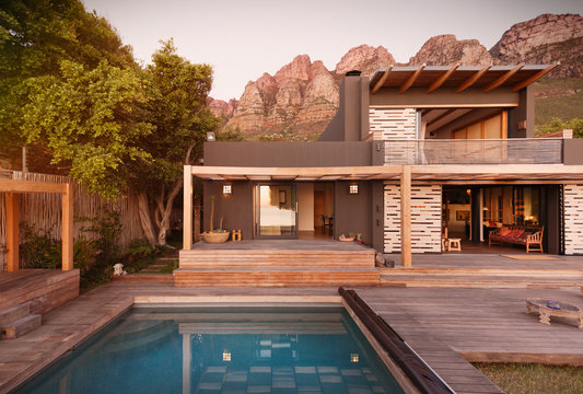Mountains behind modern, luxury home showcase exterior house with swimming pool