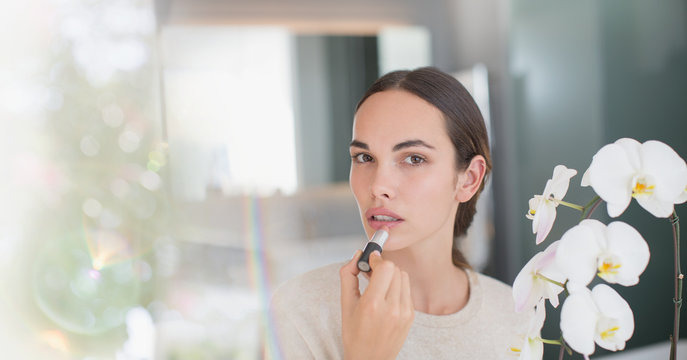 Portrait brunette woman applying lipstick