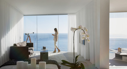 Woman standing on modern luxury home showcase balcony with sunny ocean view