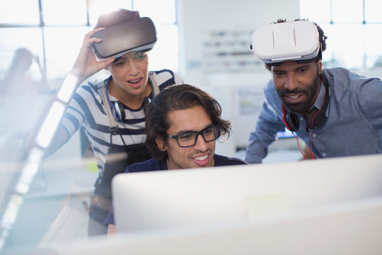 Computer programmers programming virtual reality simulators at computer in office