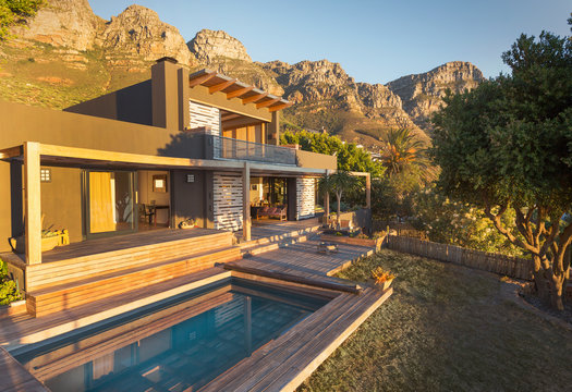 Mountains behind sunny luxury home showcase exterior house wit swimming pool