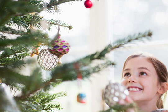 Smiling girl looking up at ornaments on Christmas tree