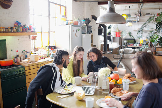 Young college student roommate friends studying at breakfast table in apartment