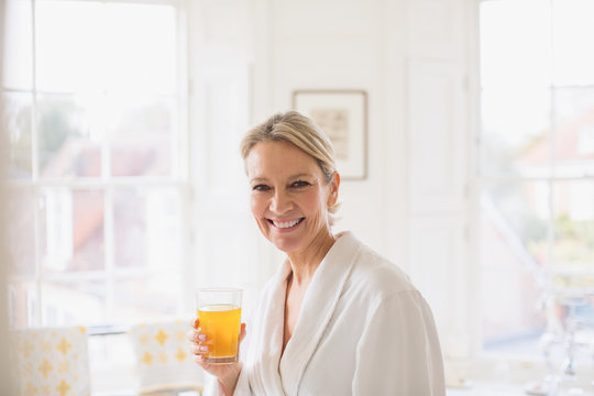 Portrait smiling, confident mature woman in bathrobe drinking juice