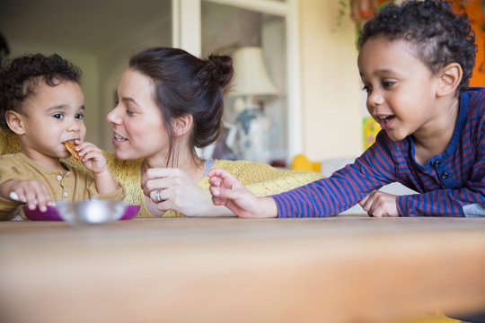 Mother watching baby son eating at table