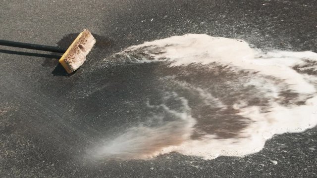 Rinse of Oil Spots Cleaned with Foam Soap on Driveway with Water, Close Up, 4k