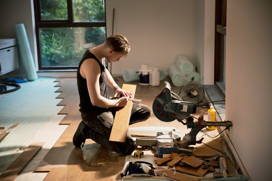Construction worker preparing hardwood flooring in house