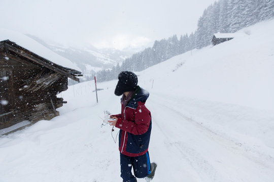 Teenage boy walking outside snowy mountain cabin, Forclaz, Switzerland