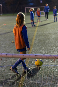 Girl soccer player practicing on field at night