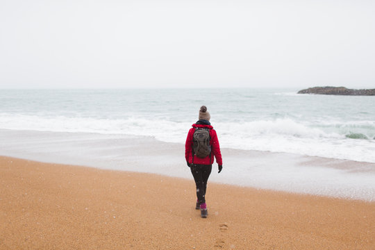Woman with backpack walking on winter beach