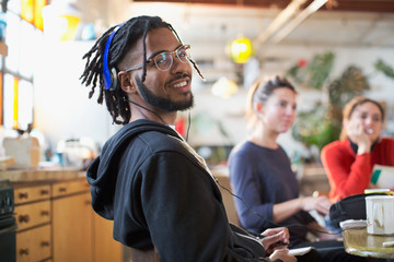 Portrait smiling young man with headphones at kitchen table