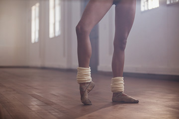 Young female ballet dancer stretching foot in dance studio