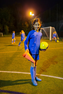 Portrait confident girl soccer player on field at night