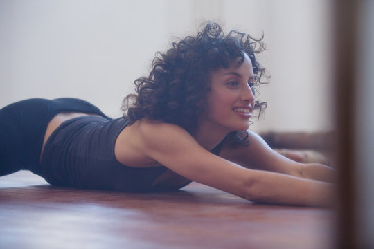 Smiling, confident young female dancer stretching in dance studio