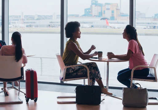 Businesswomen talking and drinking coffee in airport business lounge