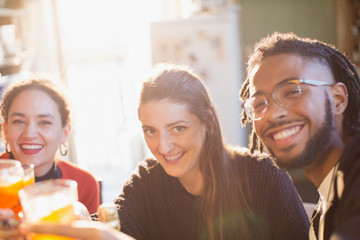 Portrait happy young adult friends toasting cocktails
