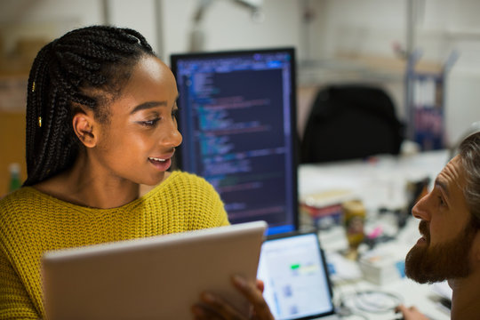 Computer programmers with digital tablet talking in office