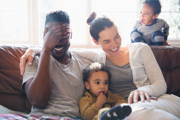 Laughing, happy multi-ethnic family on living room sofa