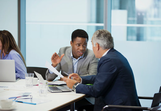 Businessmen discussing paperwork in conference room meeting