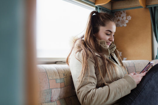 Teenage girl texting with smart phone in motor home
