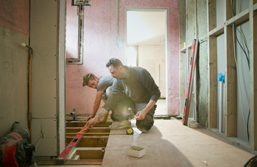 Construction workers using level tool in house