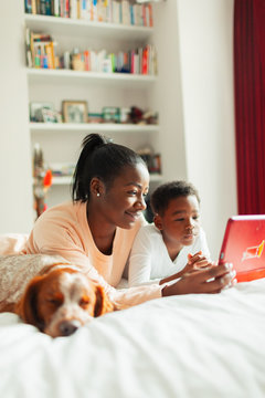 Dog sleeping next to mother and son using digital tablet