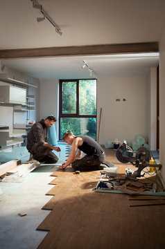 Construction workers laying hardwood flooring in house