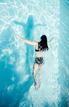 Woman in bikini swimming in sunny summer swimming pool