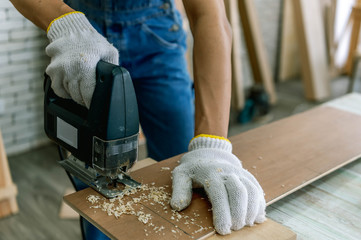 Carpenter doing his job in carpentry workshop. Portrait of adult carpenter teaching apprentice...