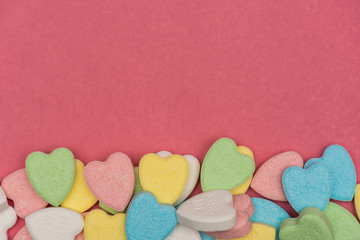 Colorful heart shaped candy on top of pink surface , valentine's day love concept
