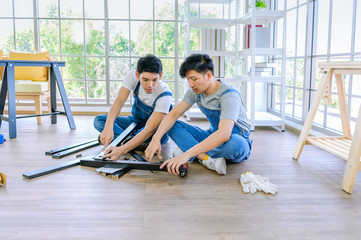Fototapeta premium profession, carpentry, woodwork and people concept - two carpenters with electric drill drilling wood plank at workshop.