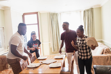 Teenage siblings setting dining room table