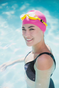 Portrait confident woman in swimming cap and goggles in swimming pool