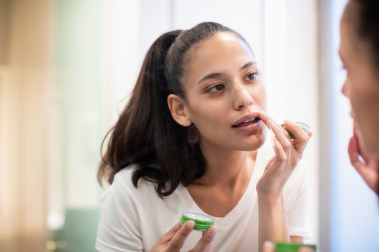 Woman applying lip balm in mirror