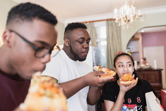 Teenage siblings eating pizza