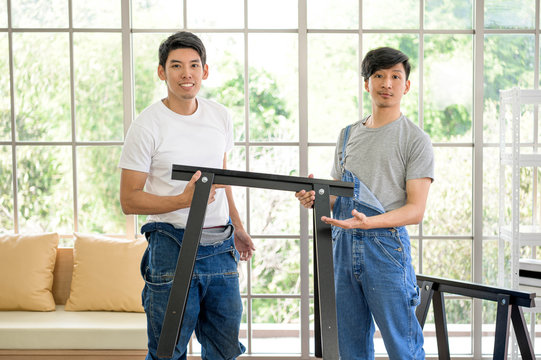 Asian Man Carpenter Working On Woodworking Table In Home Carpentry Shop. Adult Asian Man Works In Home Carpentry Shop.