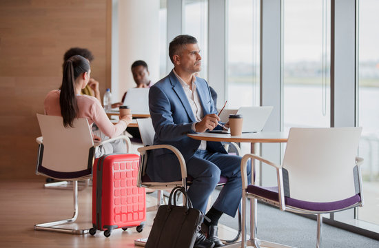Thoughtful businessman looking out window in airport business lounge