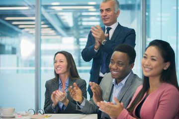 Business people smiling and clapping in conference room meeting